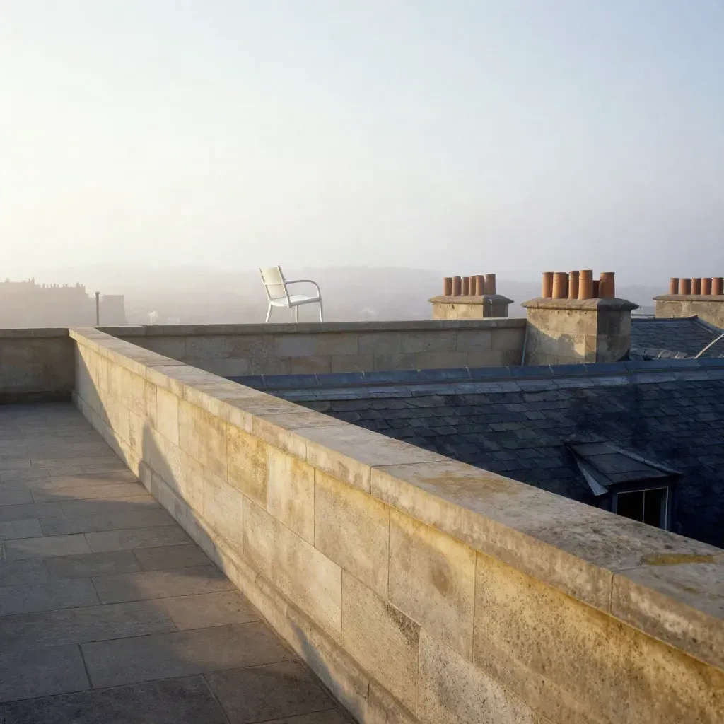 Foggy sunrise rooftop terrace with limestone parapet, pale chair and distant city rooftops.